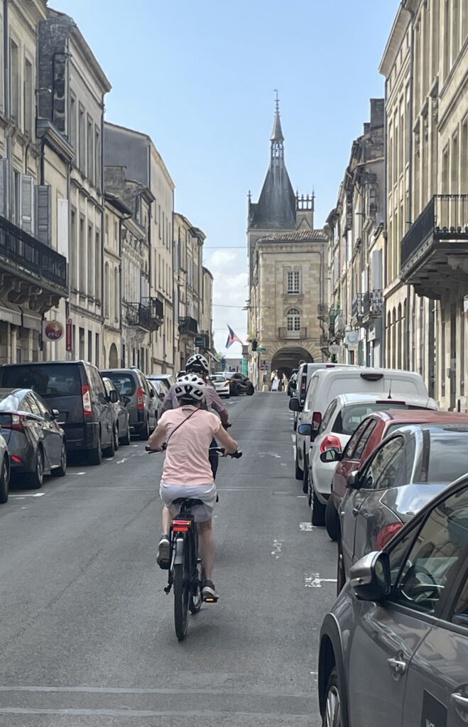 Travelers biking through the historic streets of Libourne, France, after choosing the right river cruise line for their travel style.